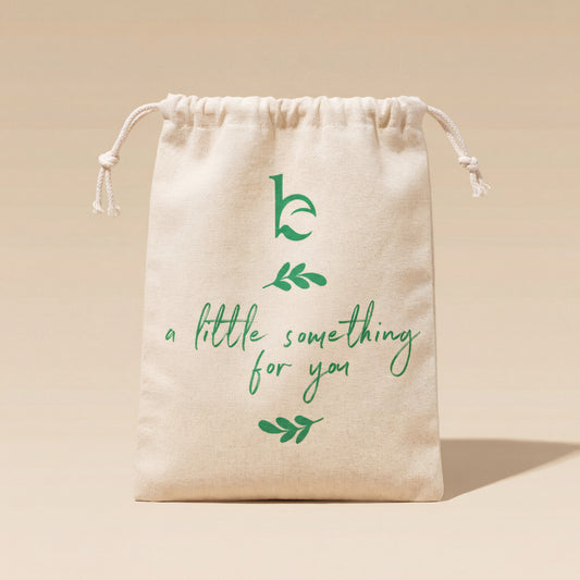 Beige drawstring bag with green text and leaf designs on a beige background