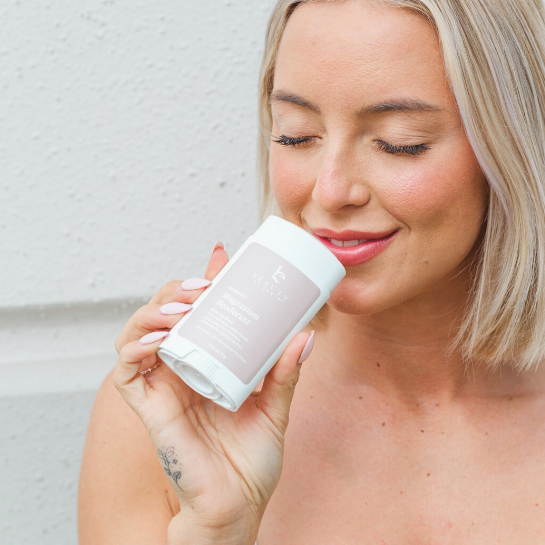 Woman holding a beauty by earth deodorant against a light background