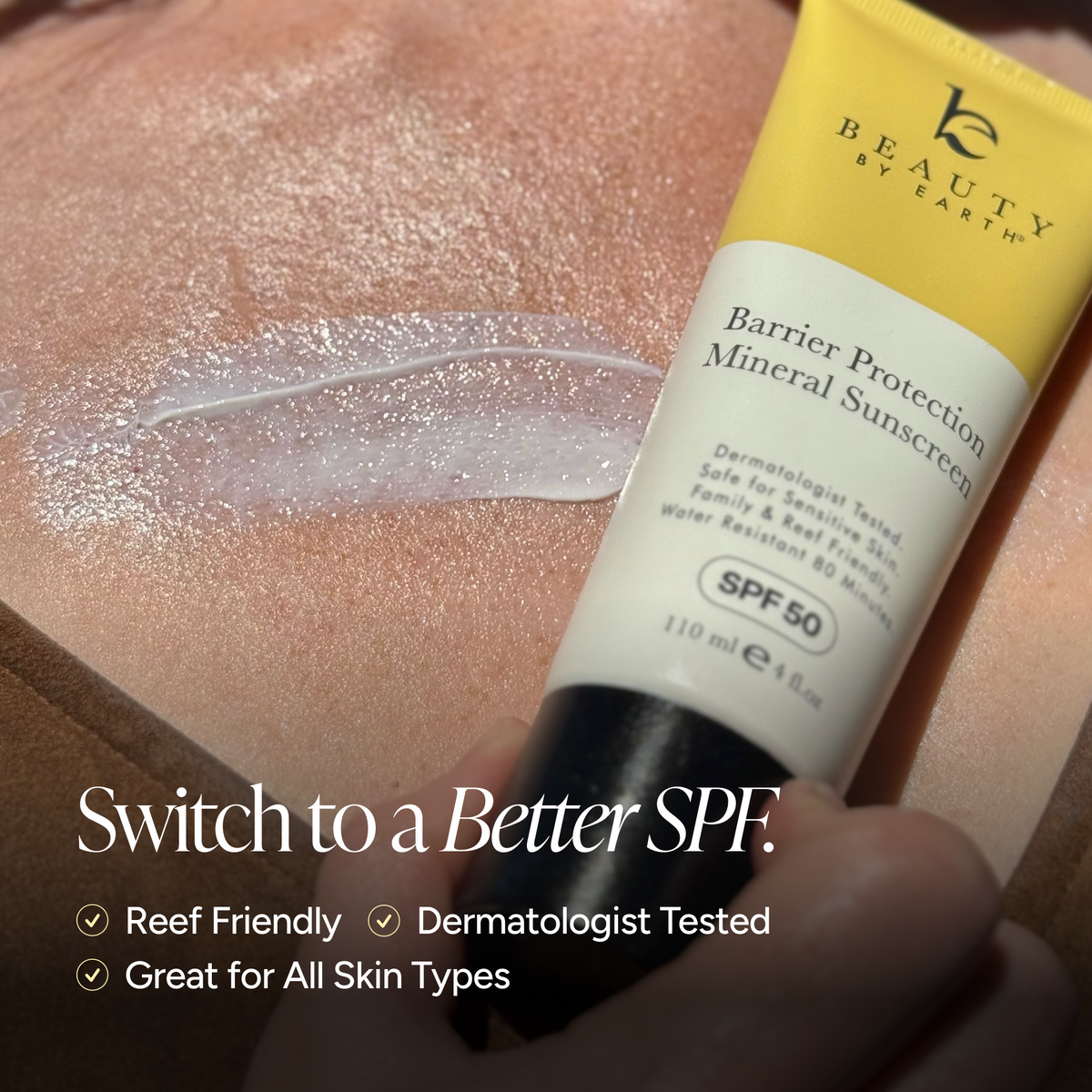 A close-up of a hand holding a tube of Beauty by Earth Barrier Protection Mineral Sunscreen SPF 50 against a skin surface with a smear of translucent sunscreen. White promotional text at the bottom reads 'Switch to a Better SPF' with bullet points about reef friendly, dermatologist tested, and great for all skin types.