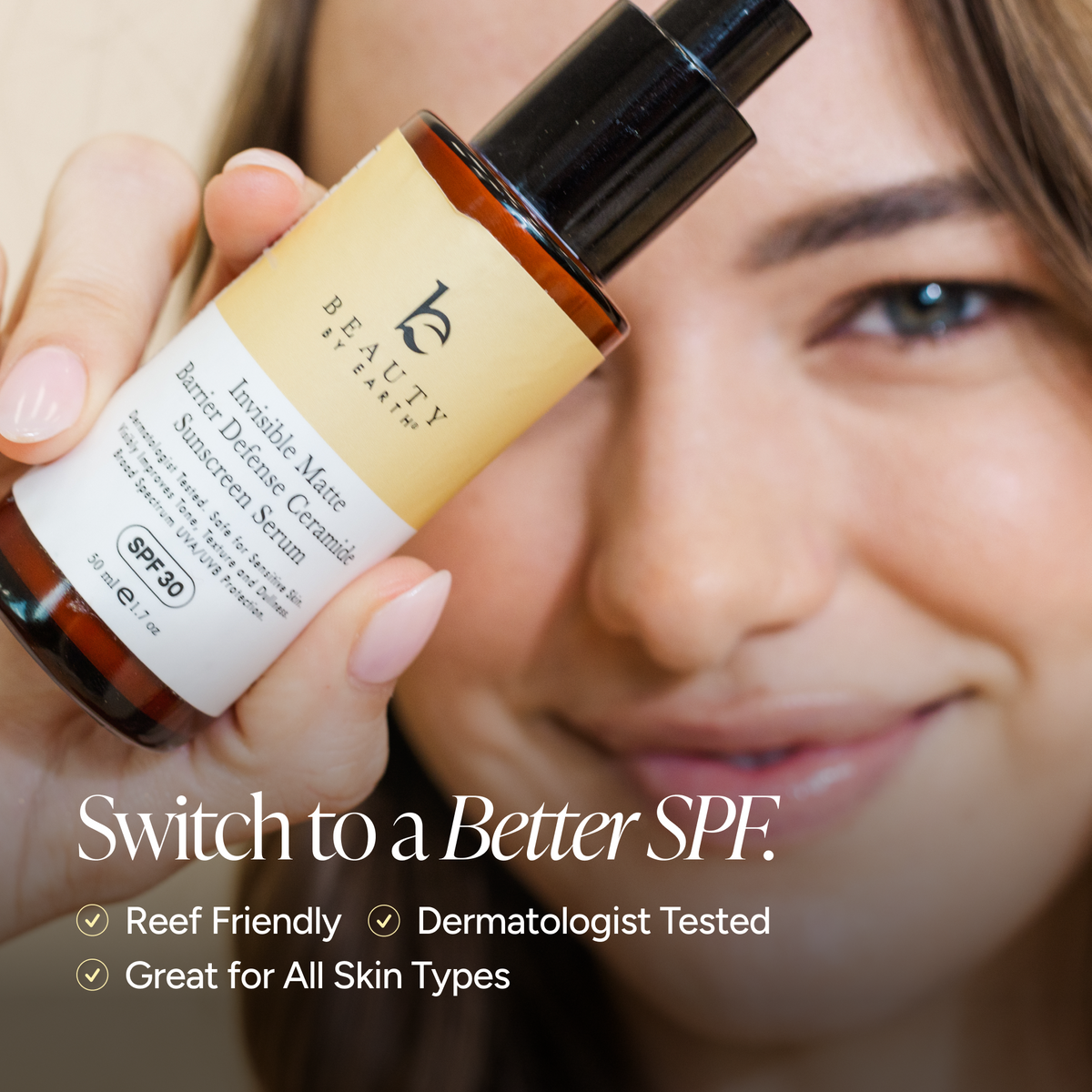 A woman holds a bottle of BEAUTY by earth Invisible Mate Sunscreen Serum in front of her face, with promotional text at the bottom reading 'Switch to a Better SPF.'.