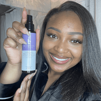 Woman holding a bottle of '100% Beauty' product in a bathroom setting