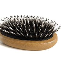 Hairbrush with wooden handle and black bristles on a white background