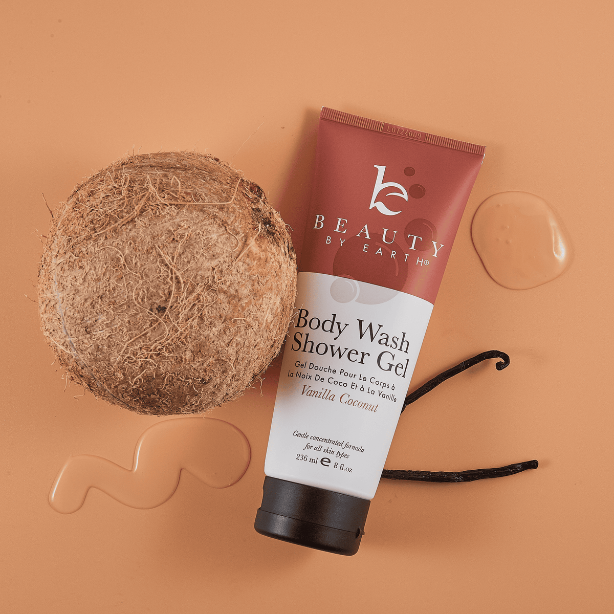Tube of 'Beauty by Earth' body wash shower gel with a coconut and vanilla bean on a peach background