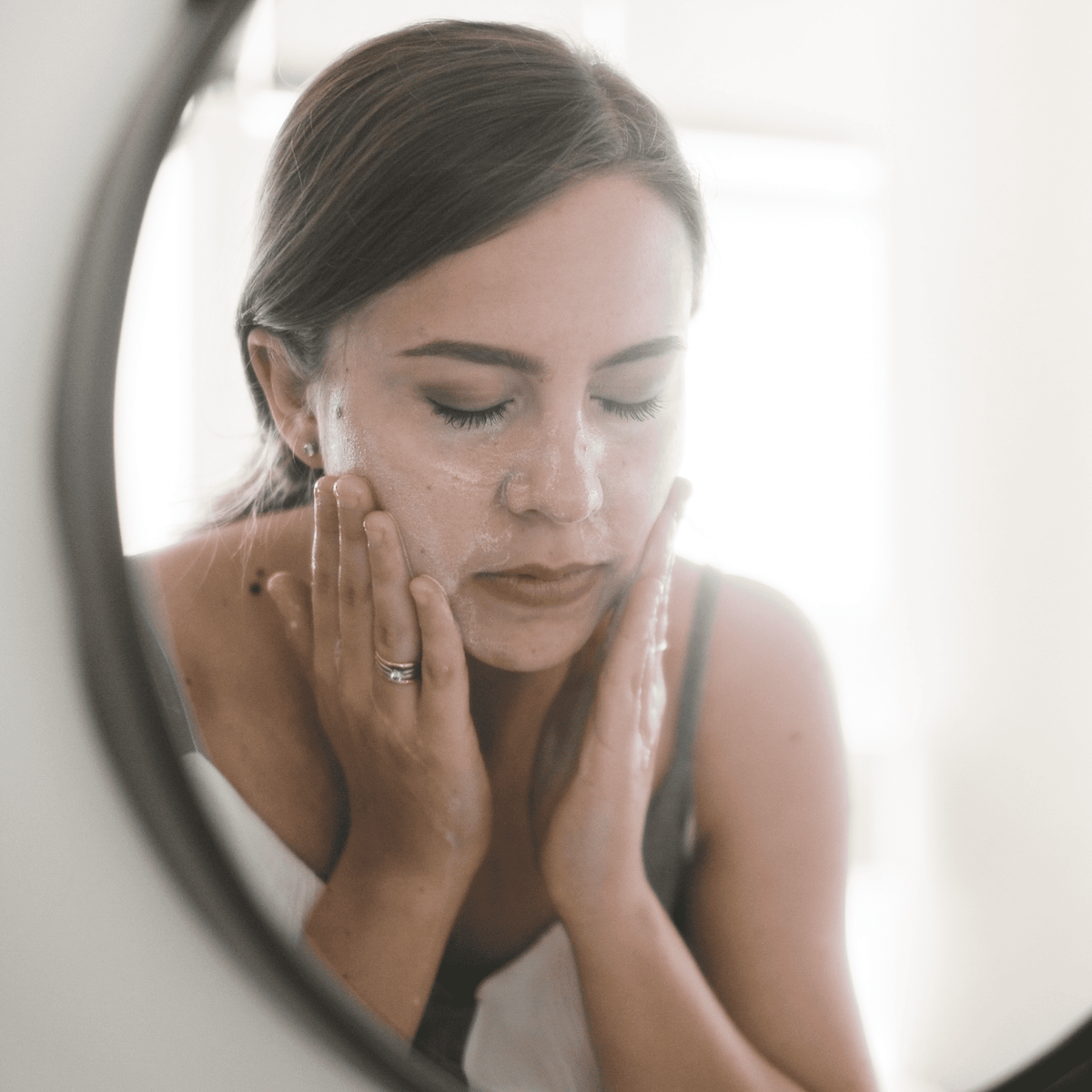 A woman applying charcoal face bar to face and washing it off demo