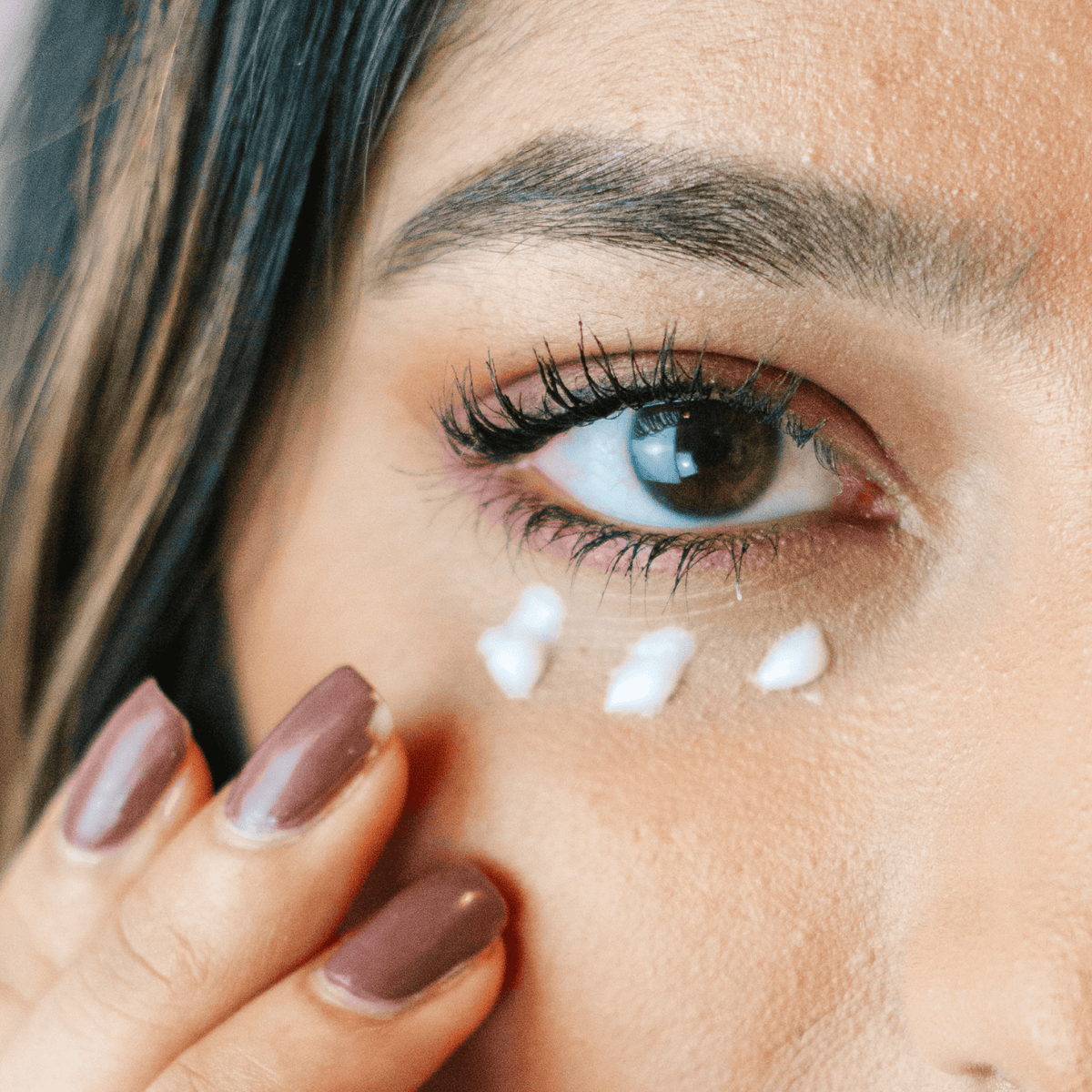Close-up of a woman's eye with coffee bean eye cream under her eye