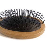 Hairbrush with black bristles on a wooden handle against a white background