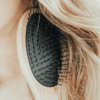 Black hairbrush being used on blonde hair