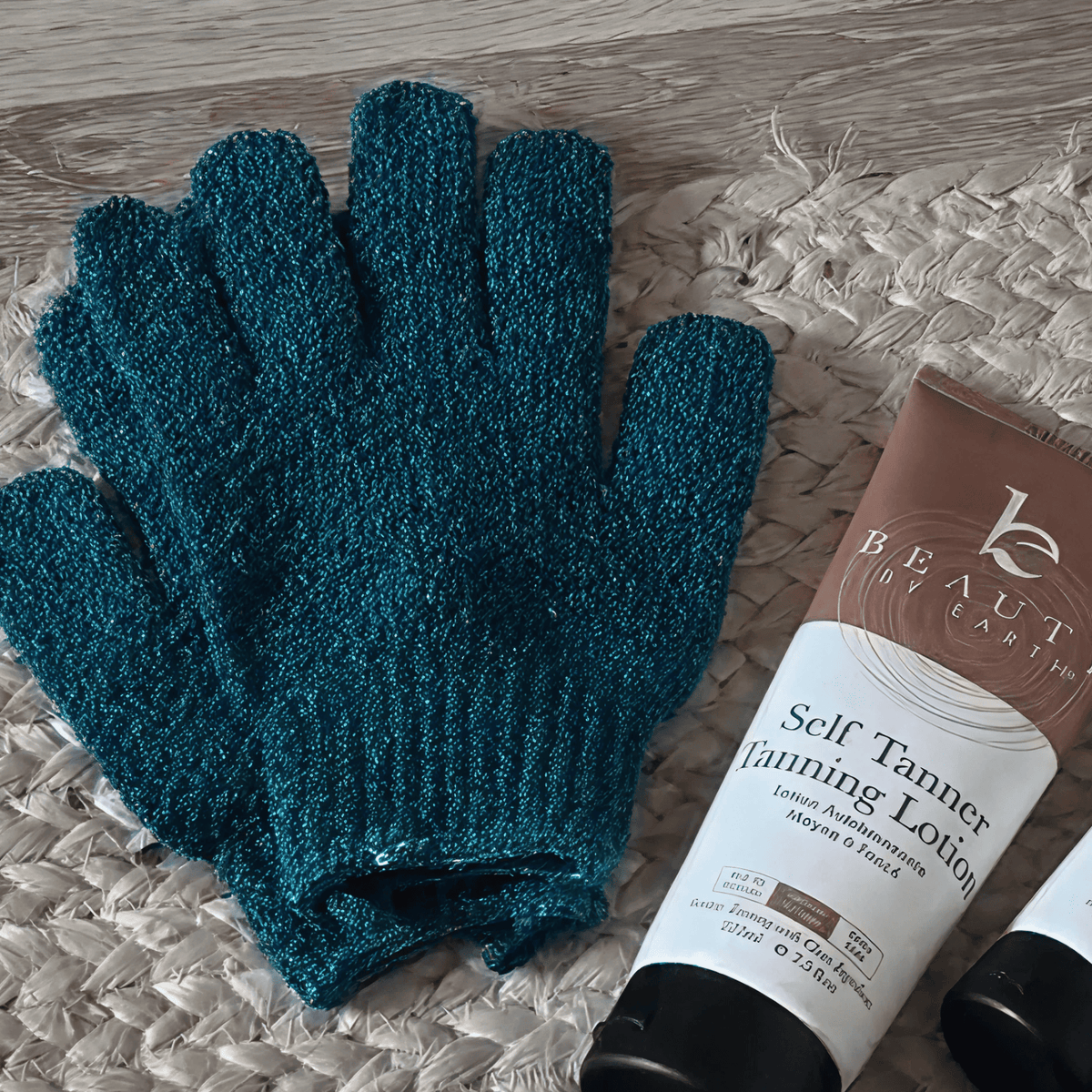 Medium exfoliating gloves and a tube of self tanning lotion on a textured surface