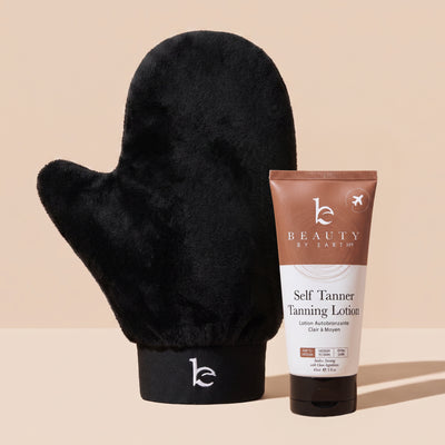 A black mitt with Beauty by Earth Self Tanner Tanning Lotion tube on a warm beige background.