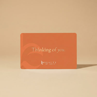 Orange card with 'Thinking of you' text and 'Beauty by Earth' logo on a beige background