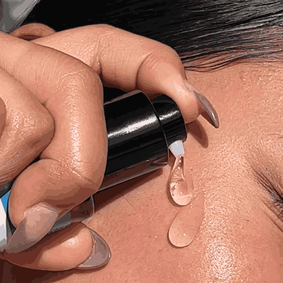 Hand applying a clear gel  to skin with a dropper.