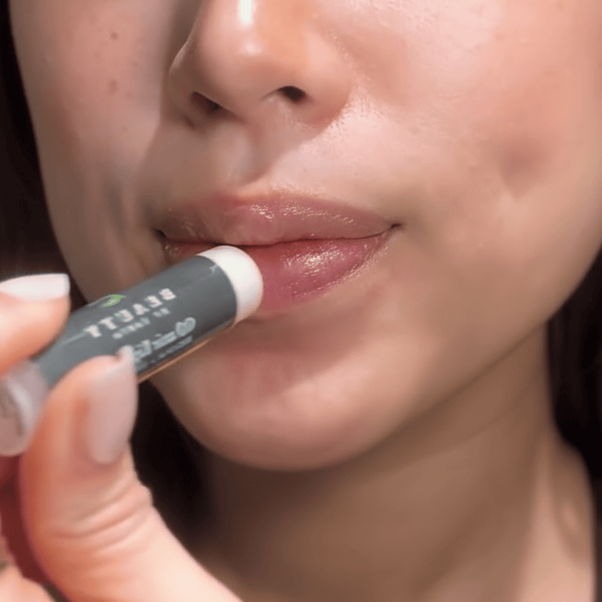 Person applying lipstick with a focus on the product and action.