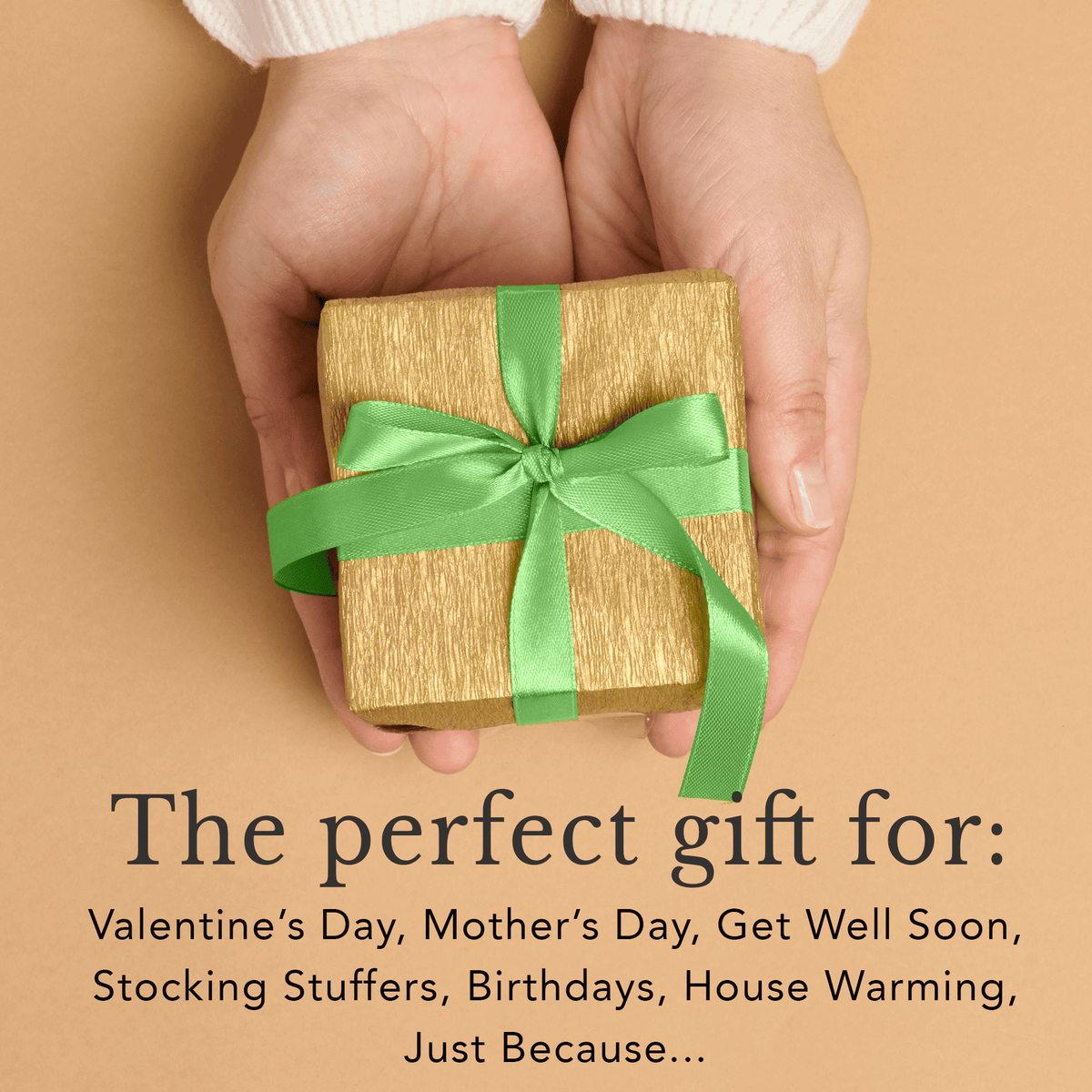 Hand holding a small gift box with a green ribbon on a beige background