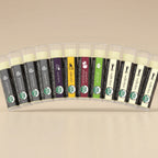 Row of lip balm tubes with various flavors on a light gray background
