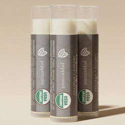 Three tubes of peppermint lip balm with USDA Organic labels on a light gray background