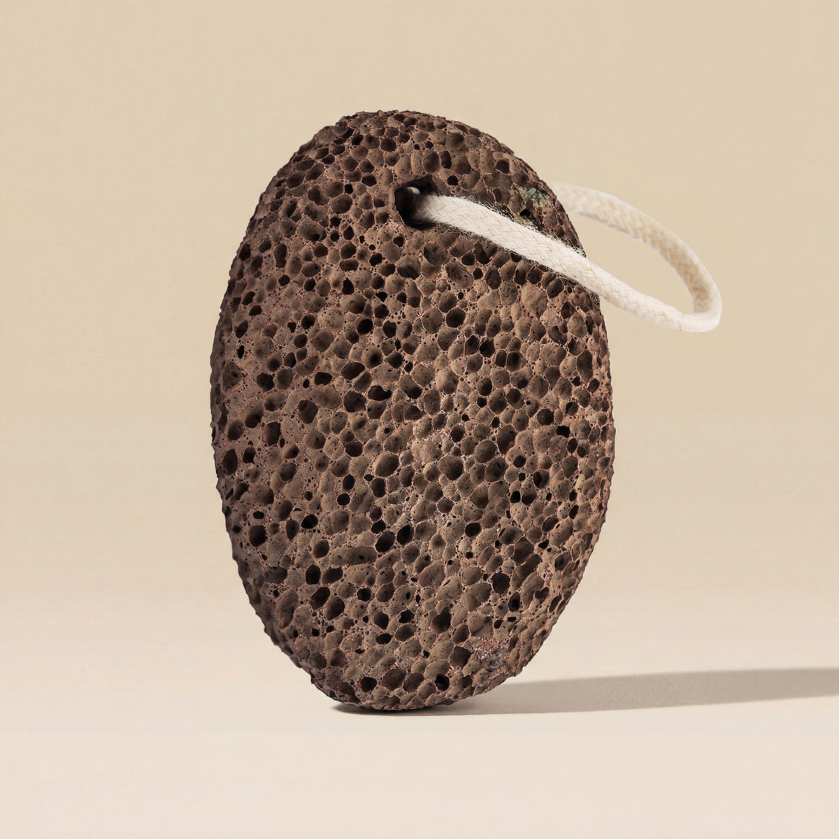 Brown pumice stone with a white string on a beige background