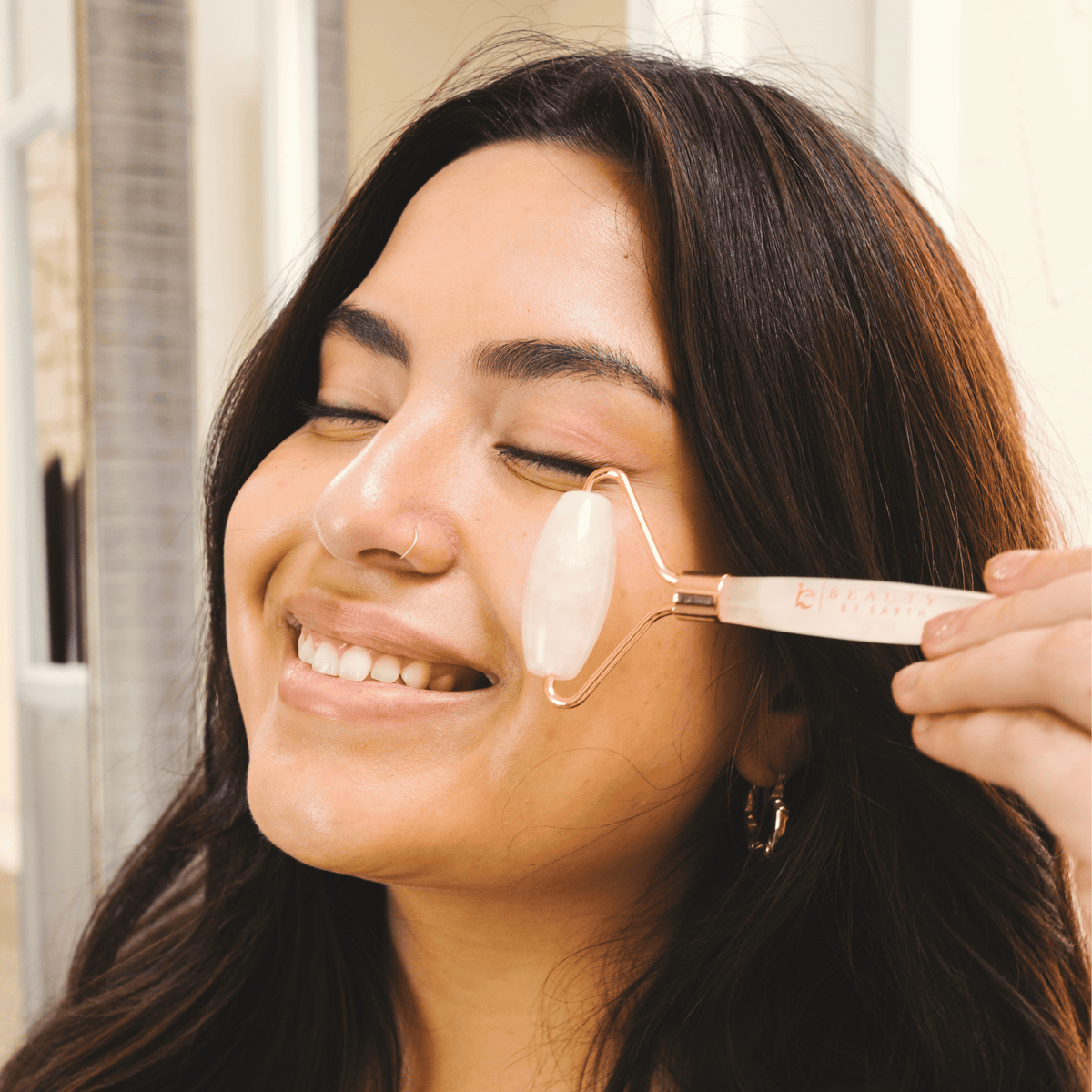 Woman using a face roller on her face with a blurred background
