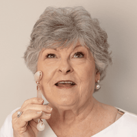 Woman holding a white earbud against a neutral background
