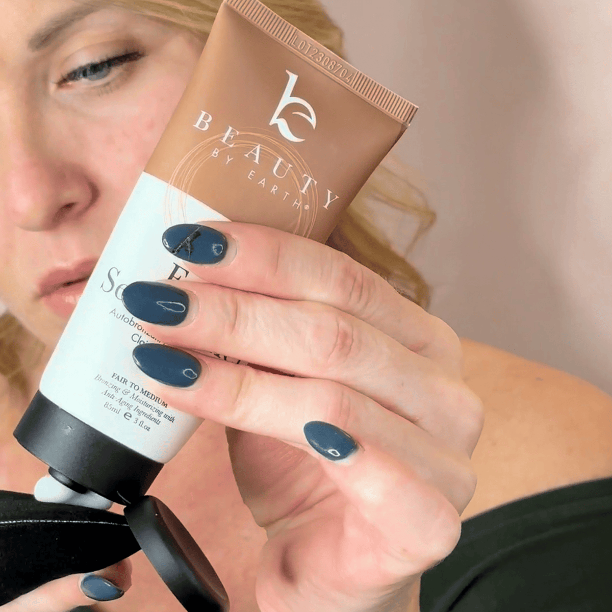 A model holding body mitt applicator for face with white lotion self tanning face lotion texture demo application.