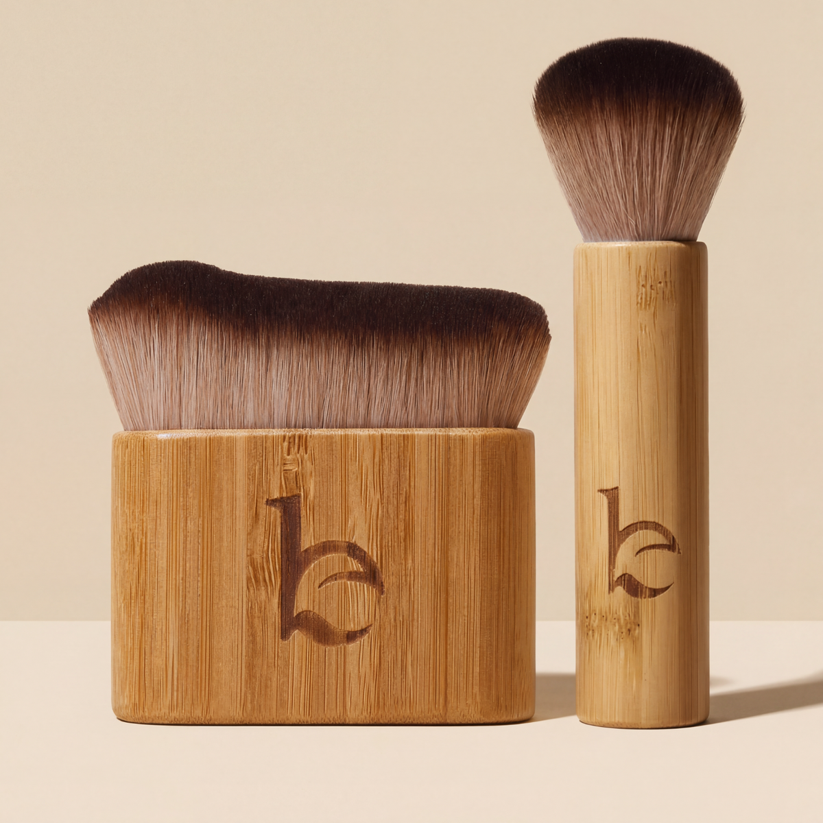 Two kabuki brushes with bristle heads on a beige background
