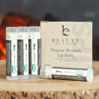 Set of Beauty by Earth organic beeswax lip balms on a wooden surface with a blurred background.
