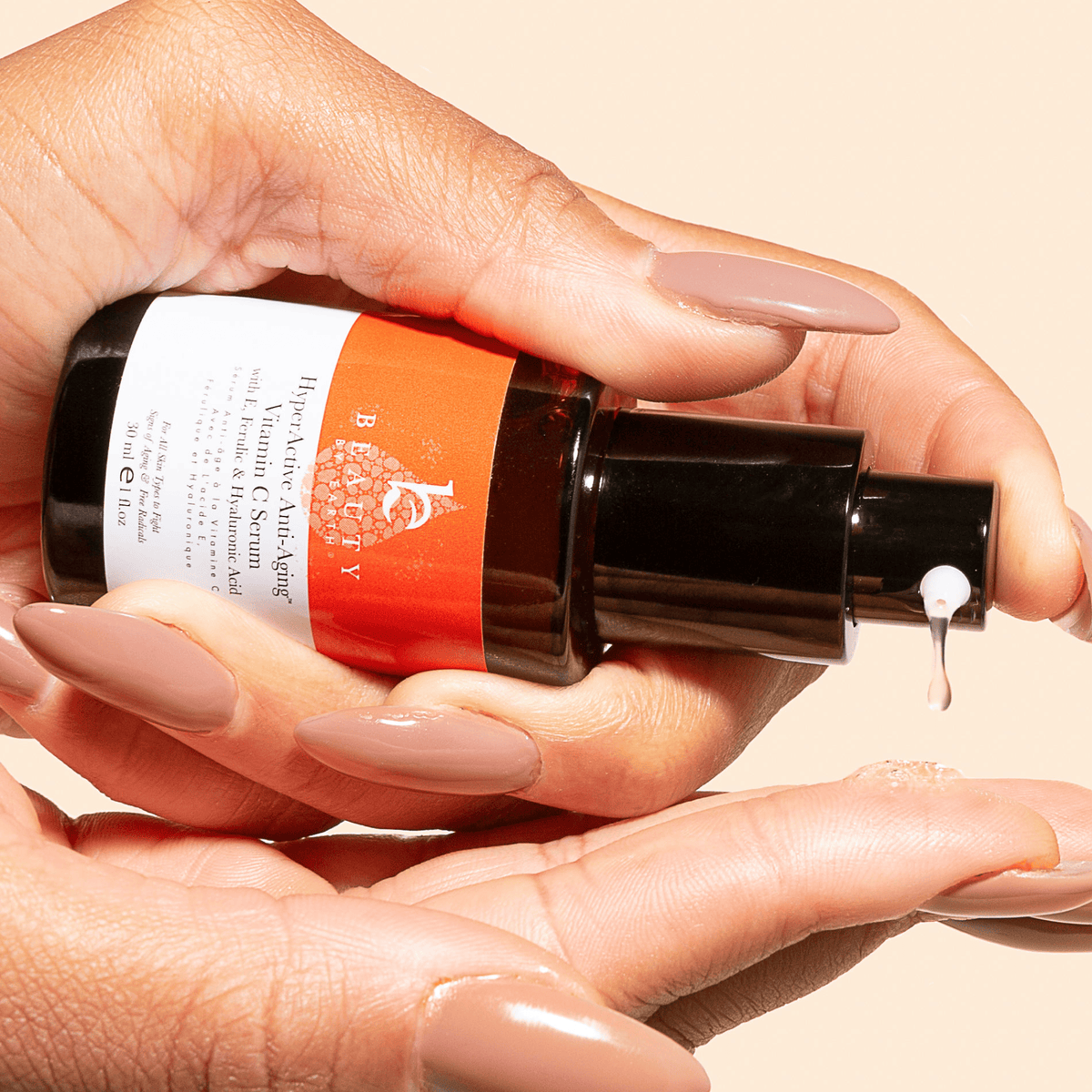 Hand holding a skincare serum bottle with a beige background