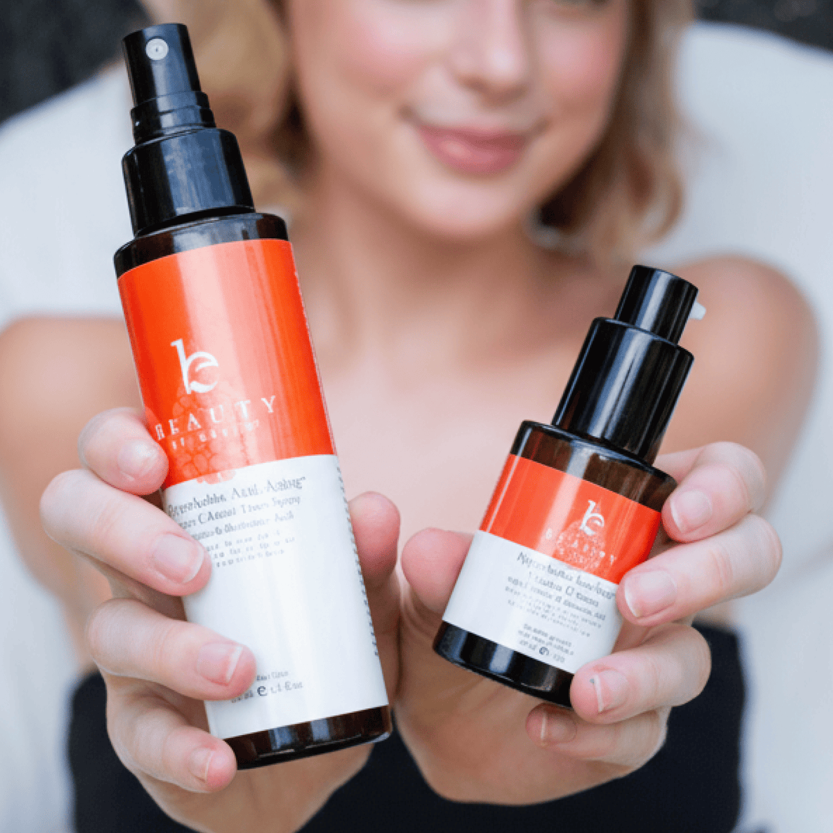 Two skincare bottles held by a person with a blurred background