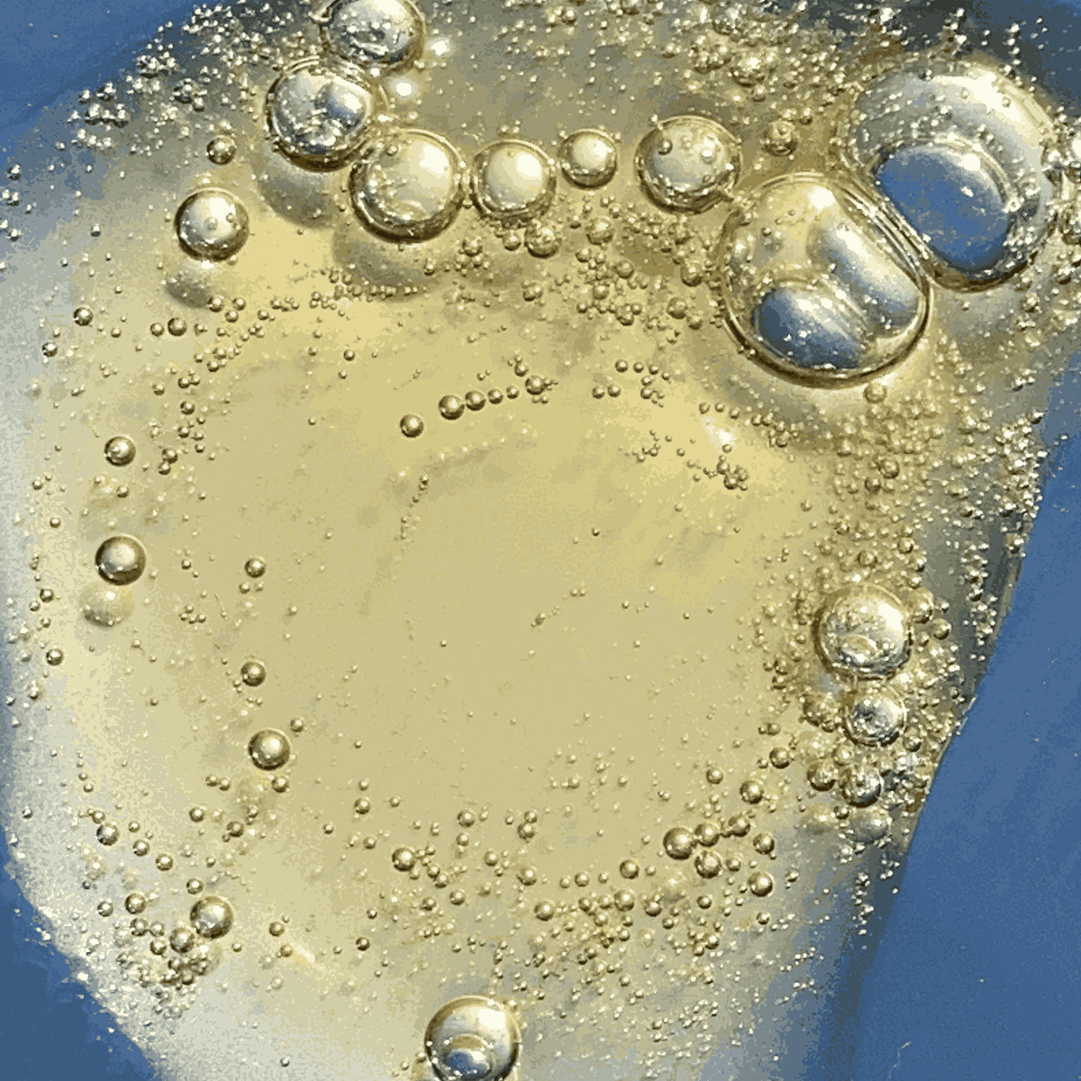 Close-up of a clear liquid with bubbles on a blue background