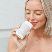 Woman holding a white container with a brand logo against a light background
